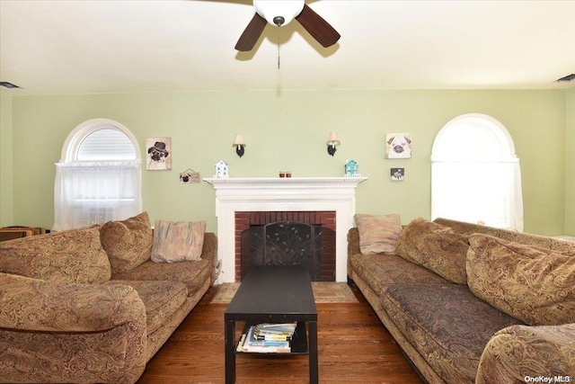 living room with ceiling fan, dark hardwood / wood-style floors, and a brick fireplace