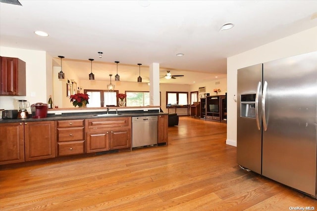 kitchen with kitchen peninsula, stainless steel appliances, ceiling fan, decorative light fixtures, and light hardwood / wood-style floors