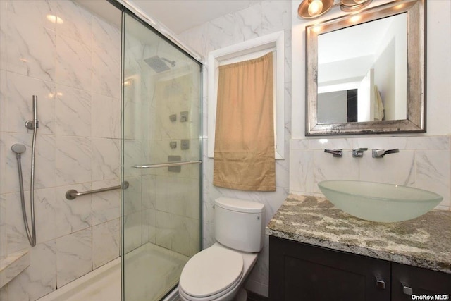 bathroom featuring vanity, toilet, tile walls, and a shower with shower door