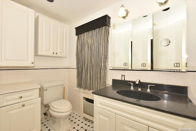 bathroom featuring tile patterned flooring, vanity, toilet, and tile walls