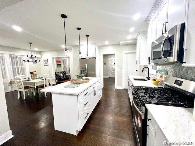 kitchen featuring white cabinets, sink, hanging light fixtures, and appliances with stainless steel finishes