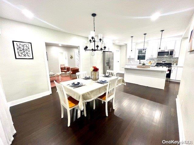 dining area with dark hardwood / wood-style floors, an inviting chandelier, and sink