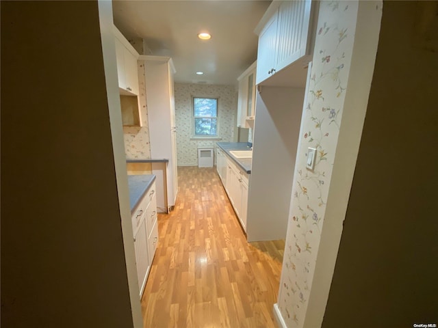 kitchen with light wood-type flooring, white cabinetry, and sink