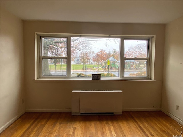 unfurnished room with a wealth of natural light, light hardwood / wood-style floors, and radiator