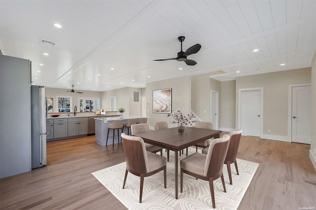 dining space featuring ceiling fan, sink, wooden ceiling, and light wood-type flooring