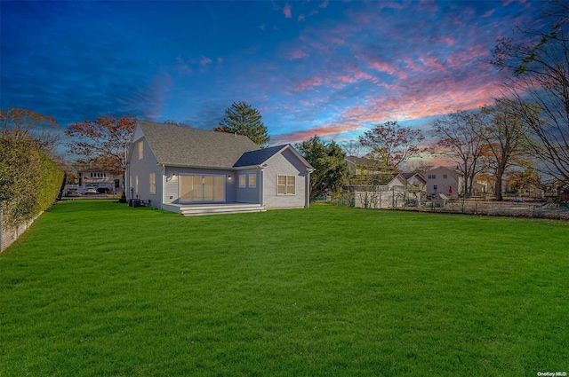 back house at dusk with a lawn