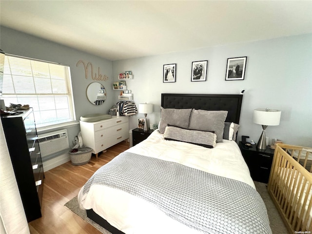 bedroom featuring light hardwood / wood-style flooring and a wall mounted air conditioner