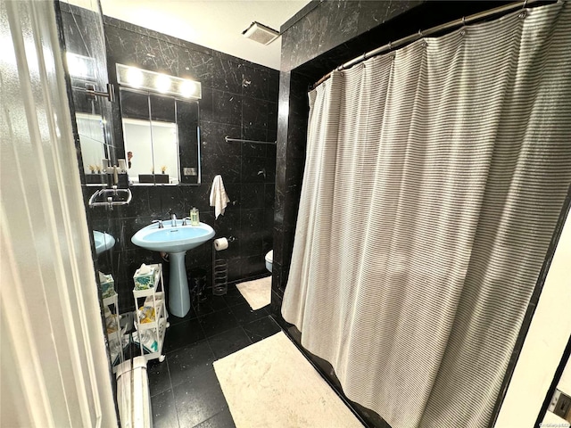 bathroom featuring sink, tile walls, and toilet