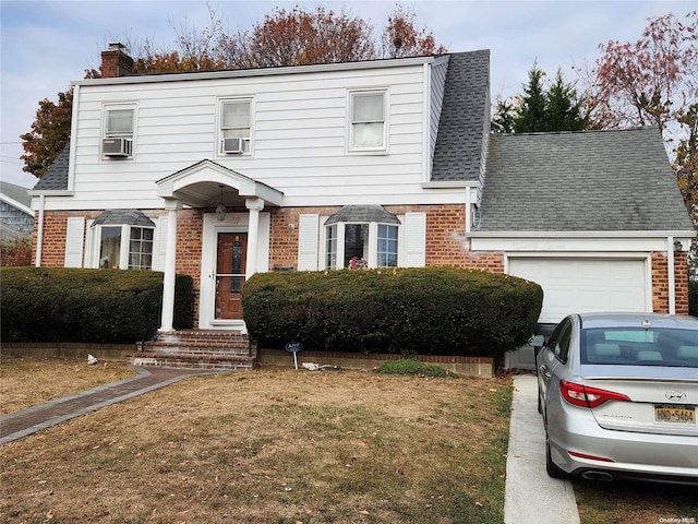 view of front of property featuring cooling unit, a front yard, and a garage