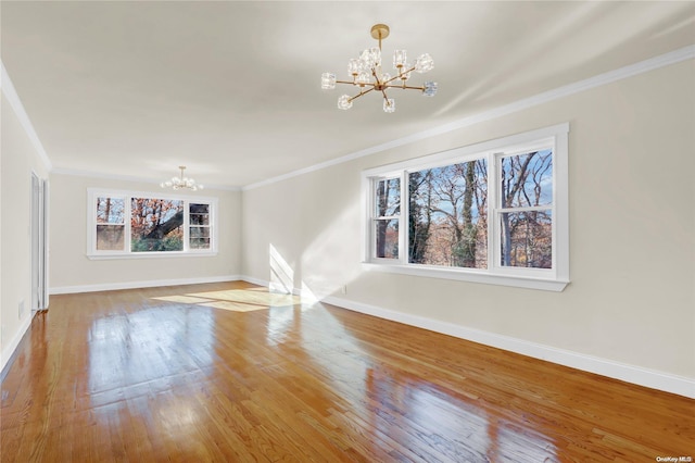 unfurnished living room with a chandelier, hardwood / wood-style flooring, and ornamental molding