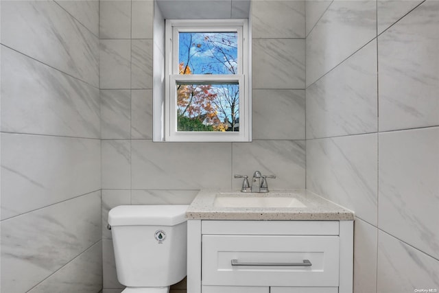 bathroom featuring vanity, toilet, and tile walls