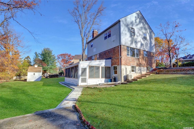 rear view of house featuring a sunroom, a storage shed, and a lawn