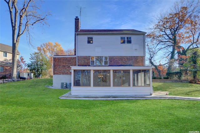 rear view of house featuring a yard and a sunroom