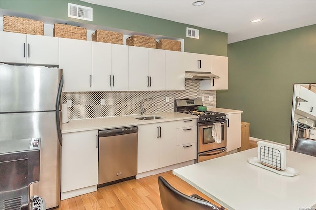 kitchen featuring exhaust hood, white cabinets, sink, appliances with stainless steel finishes, and light hardwood / wood-style floors