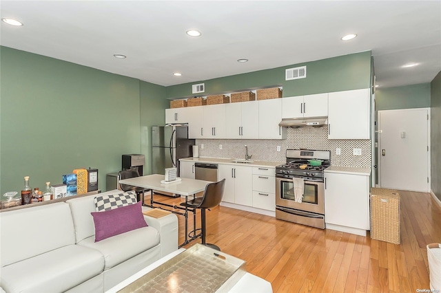 kitchen featuring decorative backsplash, appliances with stainless steel finishes, light wood-type flooring, sink, and white cabinetry