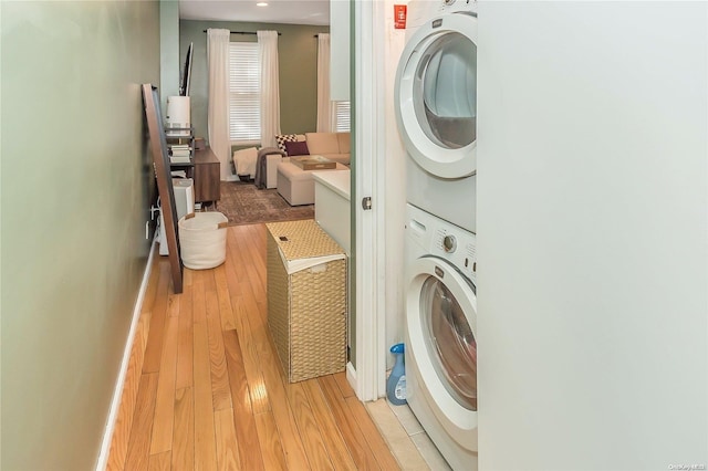 clothes washing area with light wood-type flooring and stacked washer / dryer