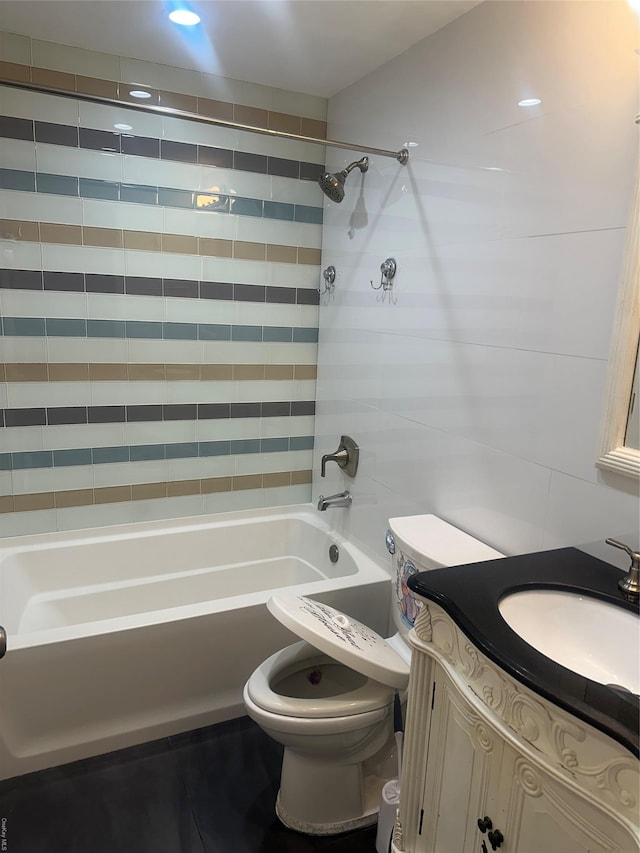 full bathroom featuring tiled shower / bath combo, vanity, and toilet