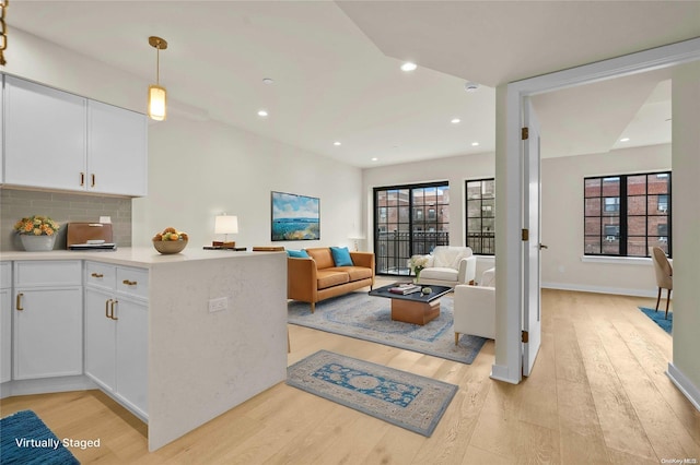 kitchen featuring light hardwood / wood-style floors, white cabinetry, hanging light fixtures, and a wealth of natural light