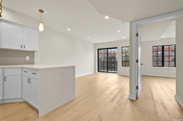 kitchen with light hardwood / wood-style flooring, white cabinets, and hanging light fixtures