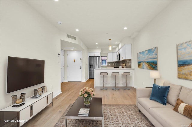 living room with light wood-type flooring and sink