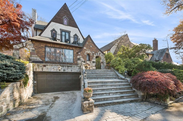 tudor home featuring a balcony and a garage