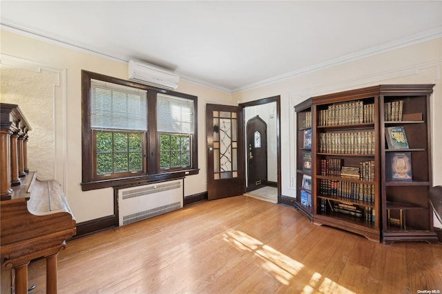 foyer featuring a wall unit AC, radiator, crown molding, and light hardwood / wood-style flooring