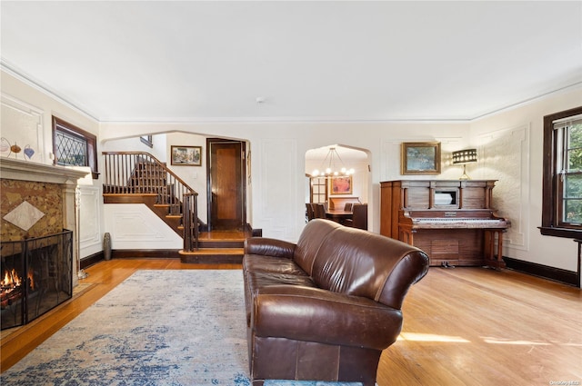 living room with a notable chandelier, light wood-type flooring, and crown molding