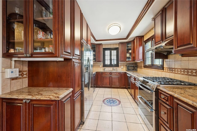 kitchen with decorative backsplash, appliances with stainless steel finishes, light stone countertops, sink, and light tile patterned floors