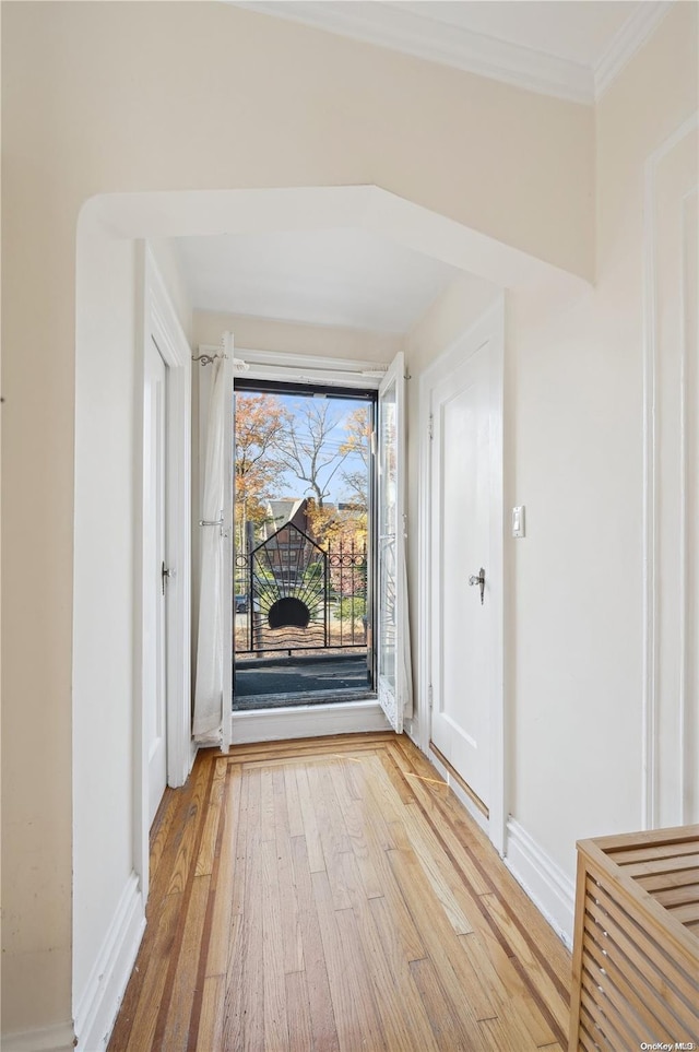 corridor with light hardwood / wood-style flooring and ornamental molding