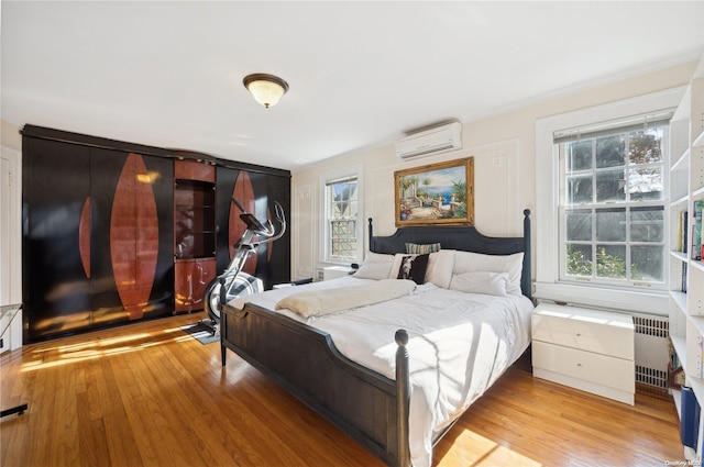 bedroom with light hardwood / wood-style floors, radiator, and a wall unit AC