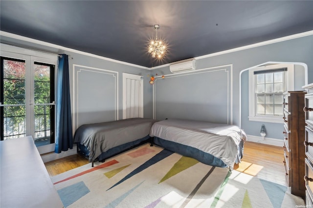 bedroom with a wall mounted air conditioner, french doors, crown molding, access to exterior, and light hardwood / wood-style floors