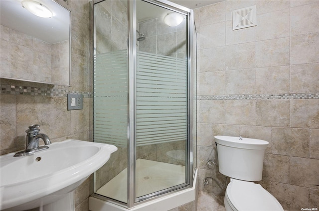 bathroom with toilet, tile walls, a shower with shower door, and sink