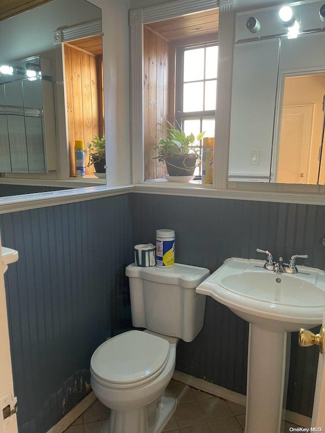 bathroom with tile patterned floors, toilet, and wood walls