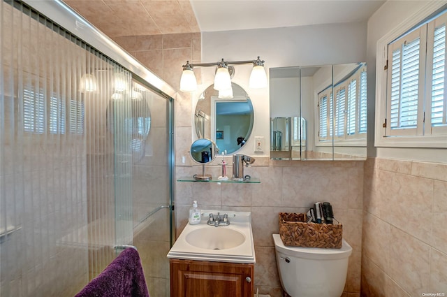 bathroom featuring vanity, toilet, tile walls, and a shower with shower door