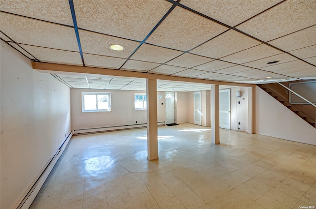 basement featuring a drop ceiling and baseboard heating