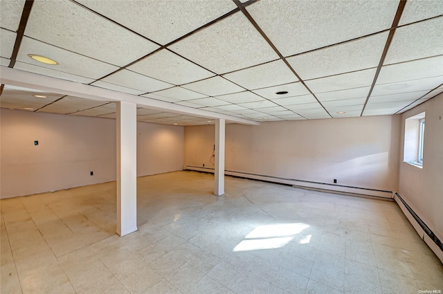 basement featuring a drop ceiling and a baseboard heating unit