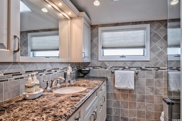 bathroom with vanity, a healthy amount of sunlight, and backsplash