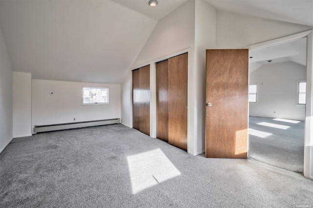 unfurnished bedroom featuring lofted ceiling, carpet floors, multiple closets, and a baseboard heating unit