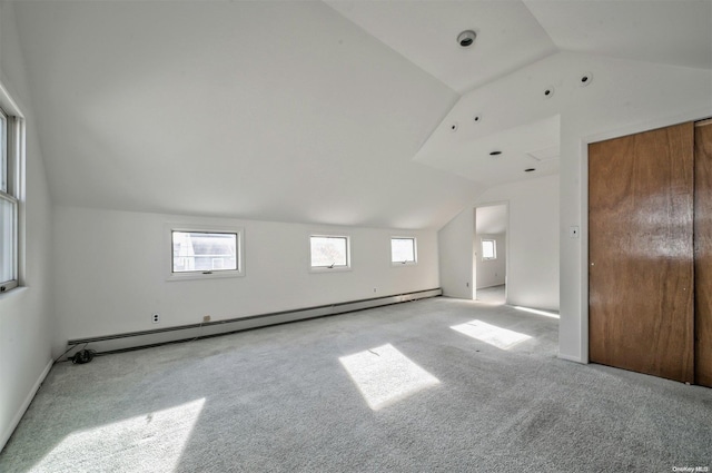 interior space with a baseboard heating unit, light colored carpet, and vaulted ceiling