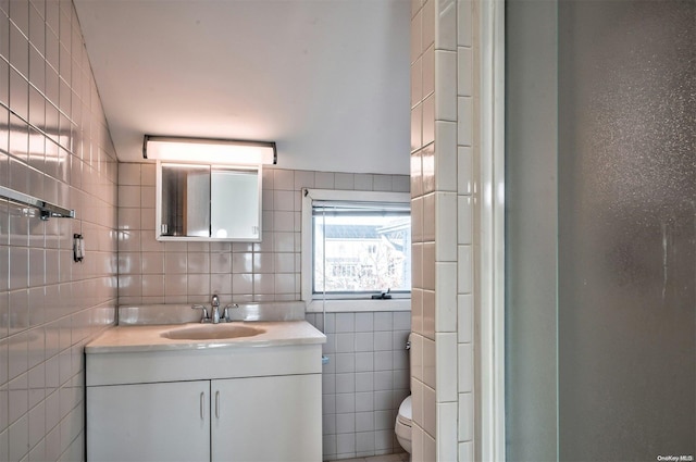 bathroom with vanity, toilet, and tile walls