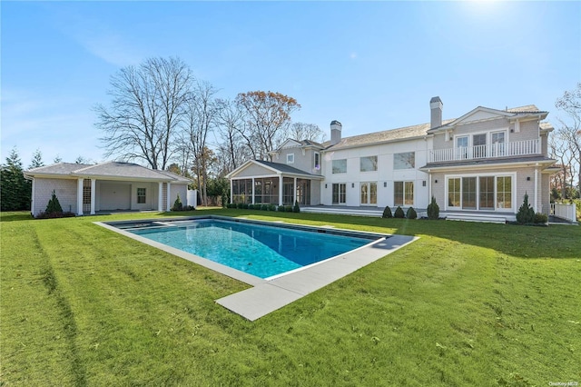 back of house with a sunroom, a balcony, and a lawn