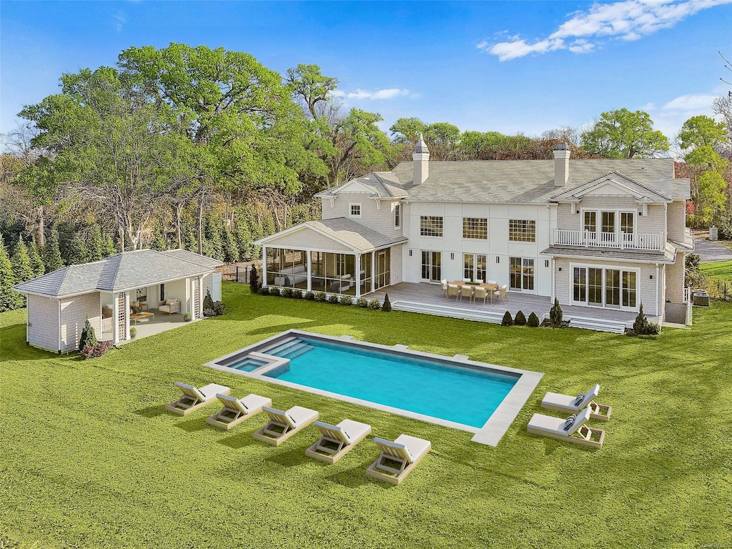14 Pen Craig Rd, Quogue, NY 11959 - rear view of house featuring a yard, a sunroom, a balcony, and an outbuilding