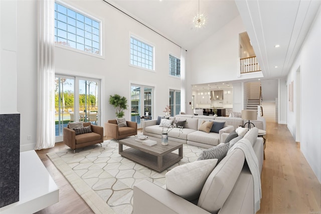 living room featuring light hardwood / wood-style flooring, a towering ceiling, and a notable chandelier