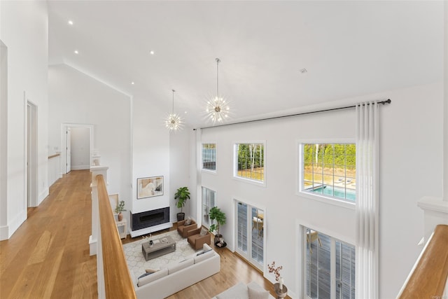 living room featuring high vaulted ceiling, a notable chandelier, and light wood-type flooring