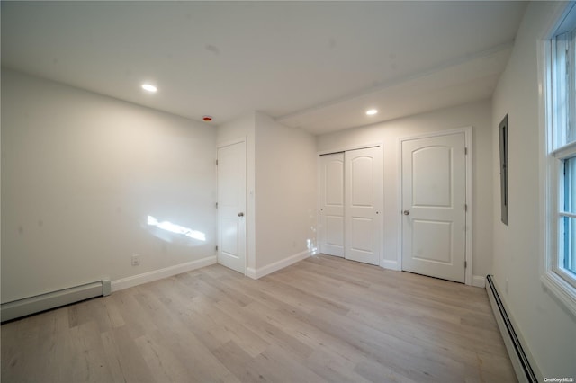 unfurnished bedroom with light wood-type flooring and a baseboard radiator