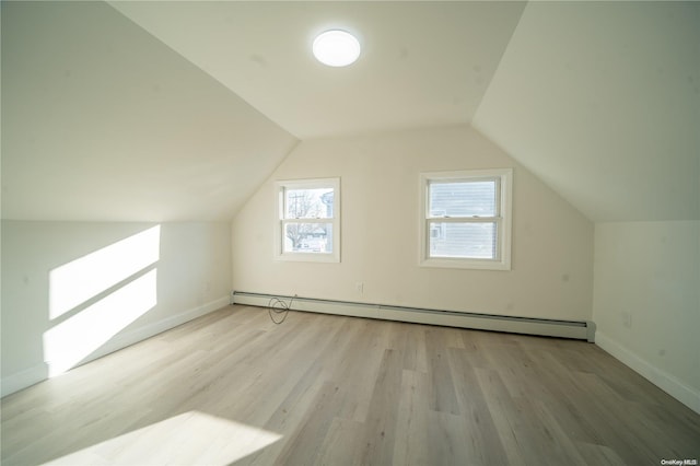 additional living space featuring baseboard heating, light hardwood / wood-style flooring, and lofted ceiling