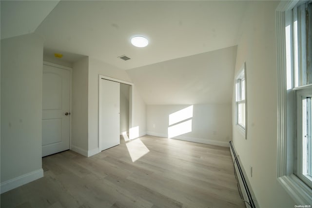 bonus room featuring light hardwood / wood-style flooring, vaulted ceiling, and a baseboard heating unit