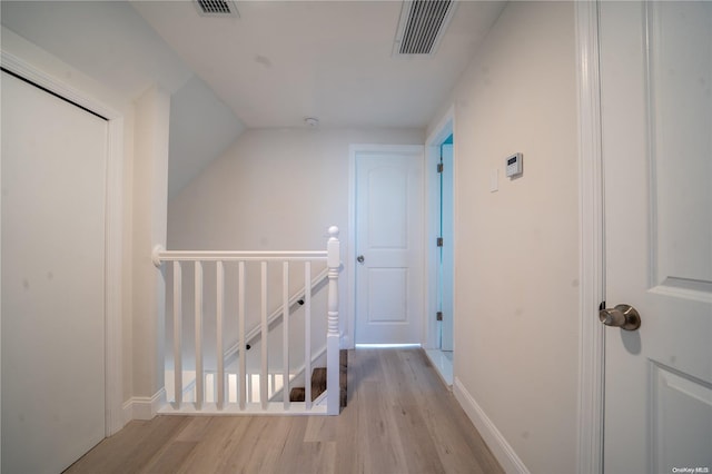 corridor featuring light wood-type flooring and lofted ceiling