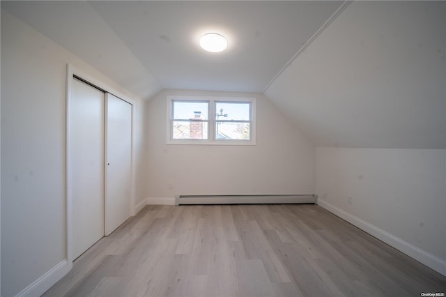 bonus room with light hardwood / wood-style floors, lofted ceiling, and a baseboard heating unit