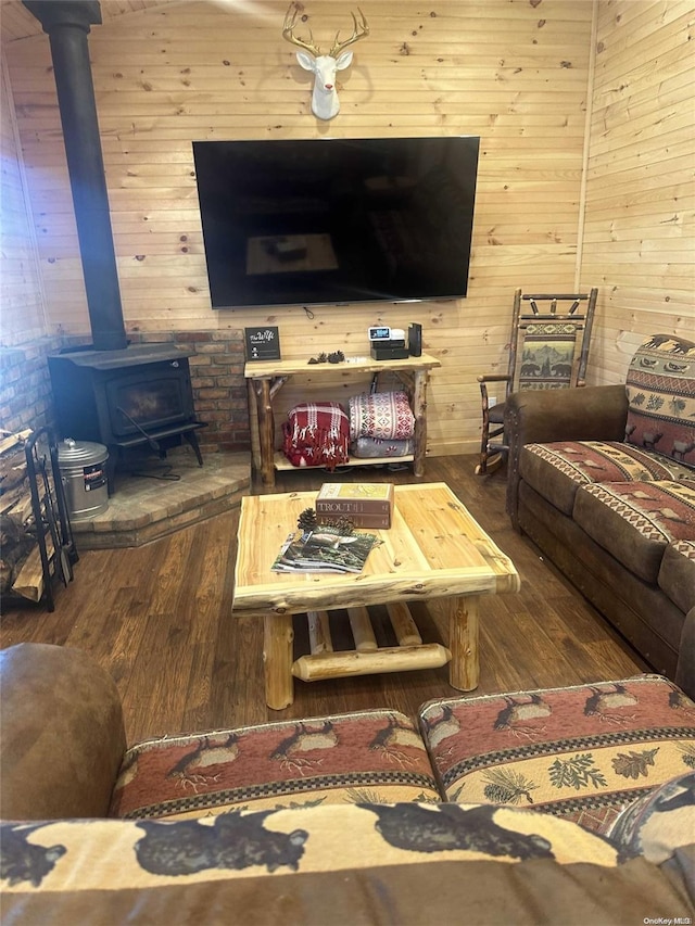 living room with a wood stove, wood walls, and hardwood / wood-style flooring